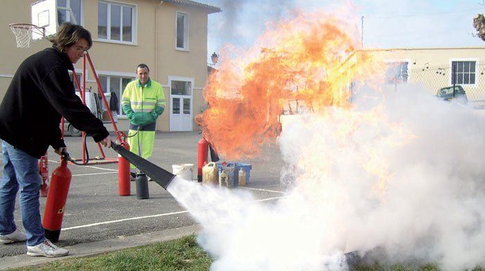 Un homme utilise un extincteur pour éteindre un incendie.