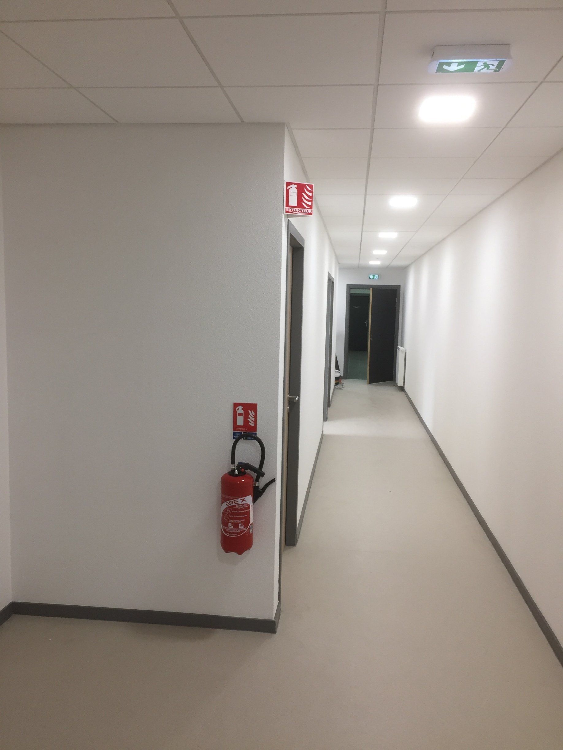 Un long couloir avec un extincteur sur le mur