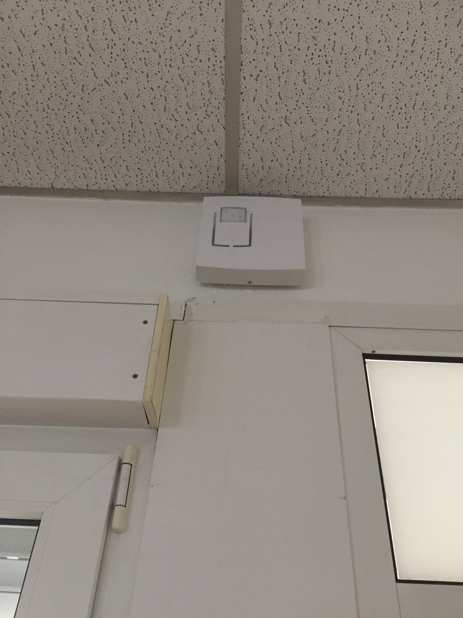 Un interrupteur blanc est monté sur un mur blanc à côté d'une porte.
