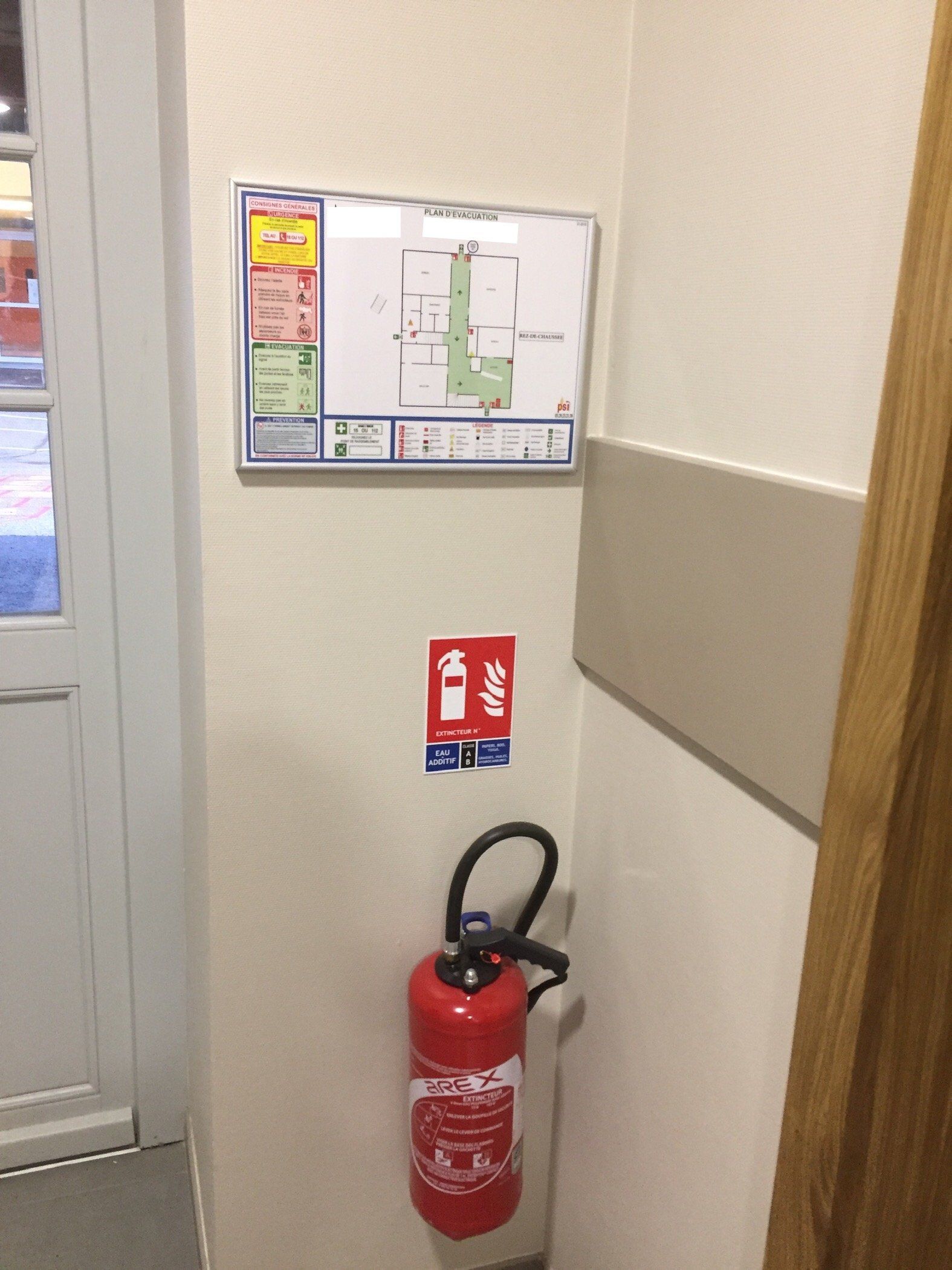 Un extincteur est accroché au mur à côté d'une carte.