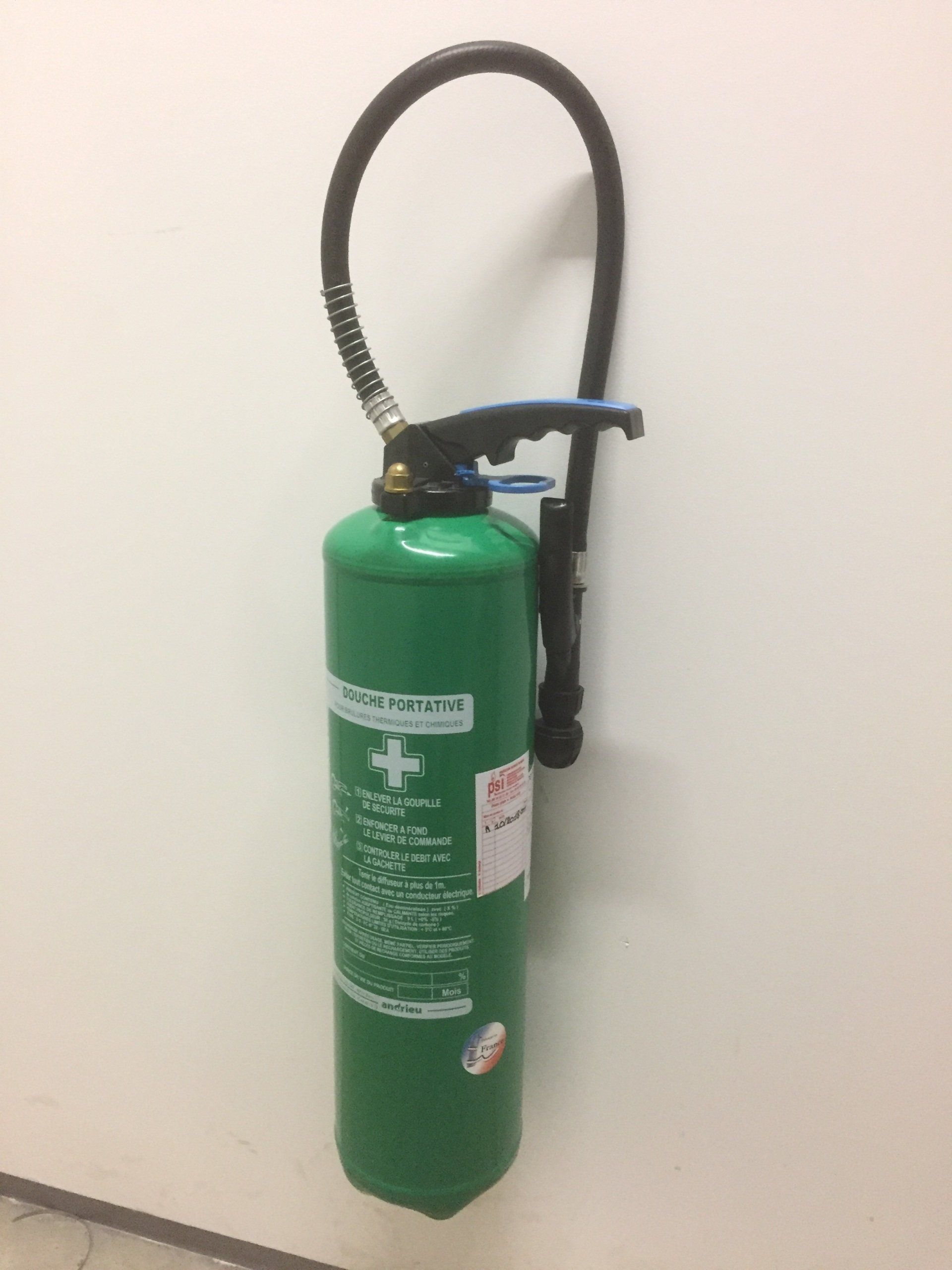 Un extincteur vert est accroché sur un mur blanc