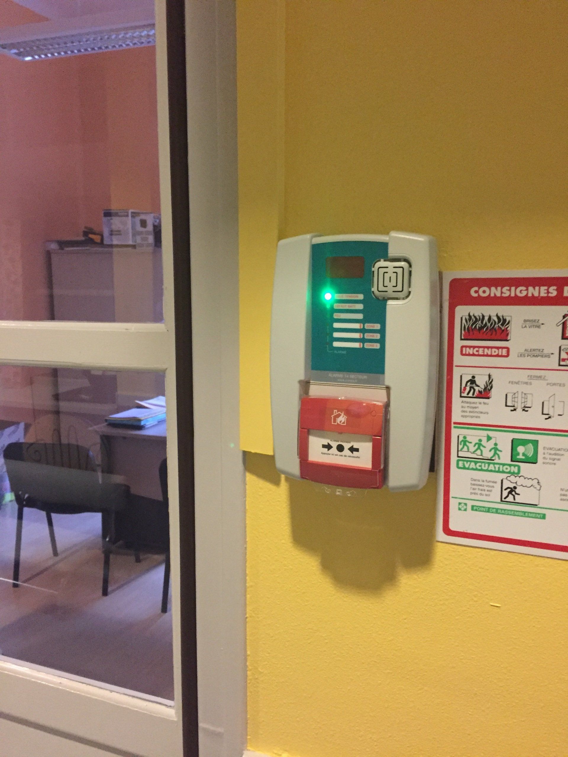 Un mur jaune avec une alarme incendie dessus