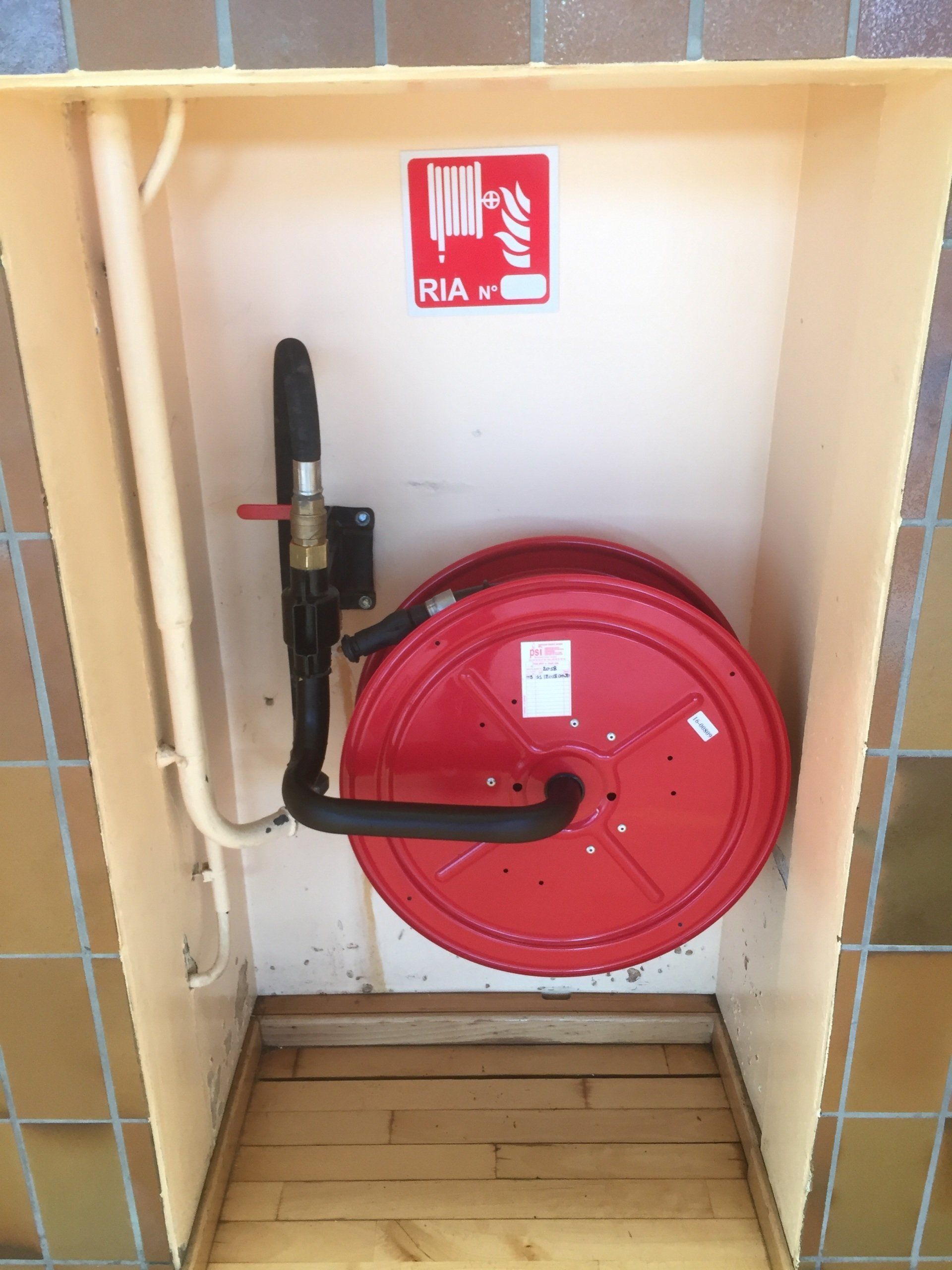Un tuyau d'incendie rouge dans une boîte avec un panneau indiquant rua