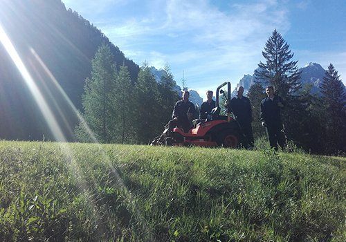 un taglia erba e quattro uomini accanto a un prato
