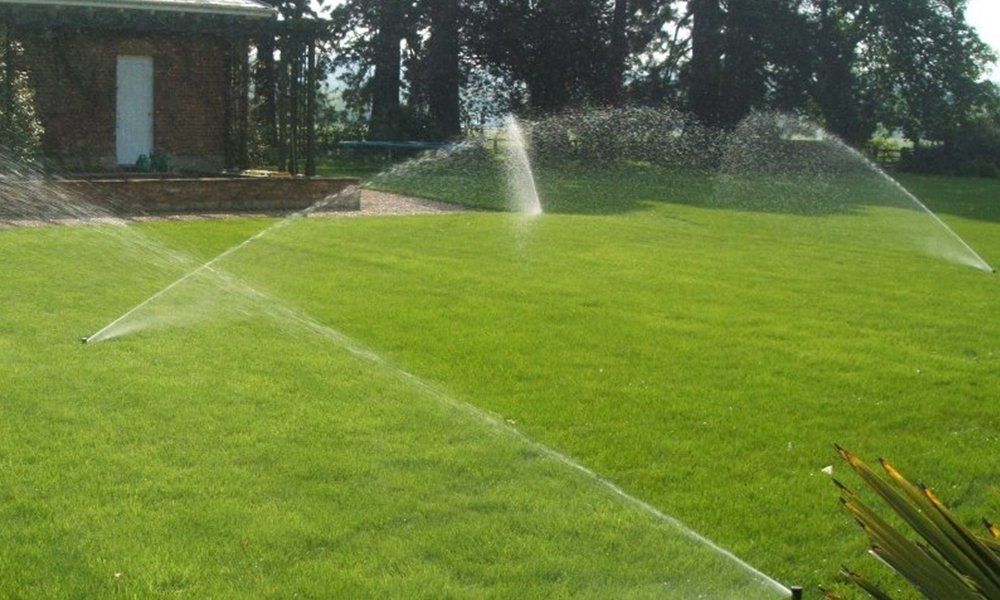 dei getti d’acqua di alcuni irrigatori in un prato