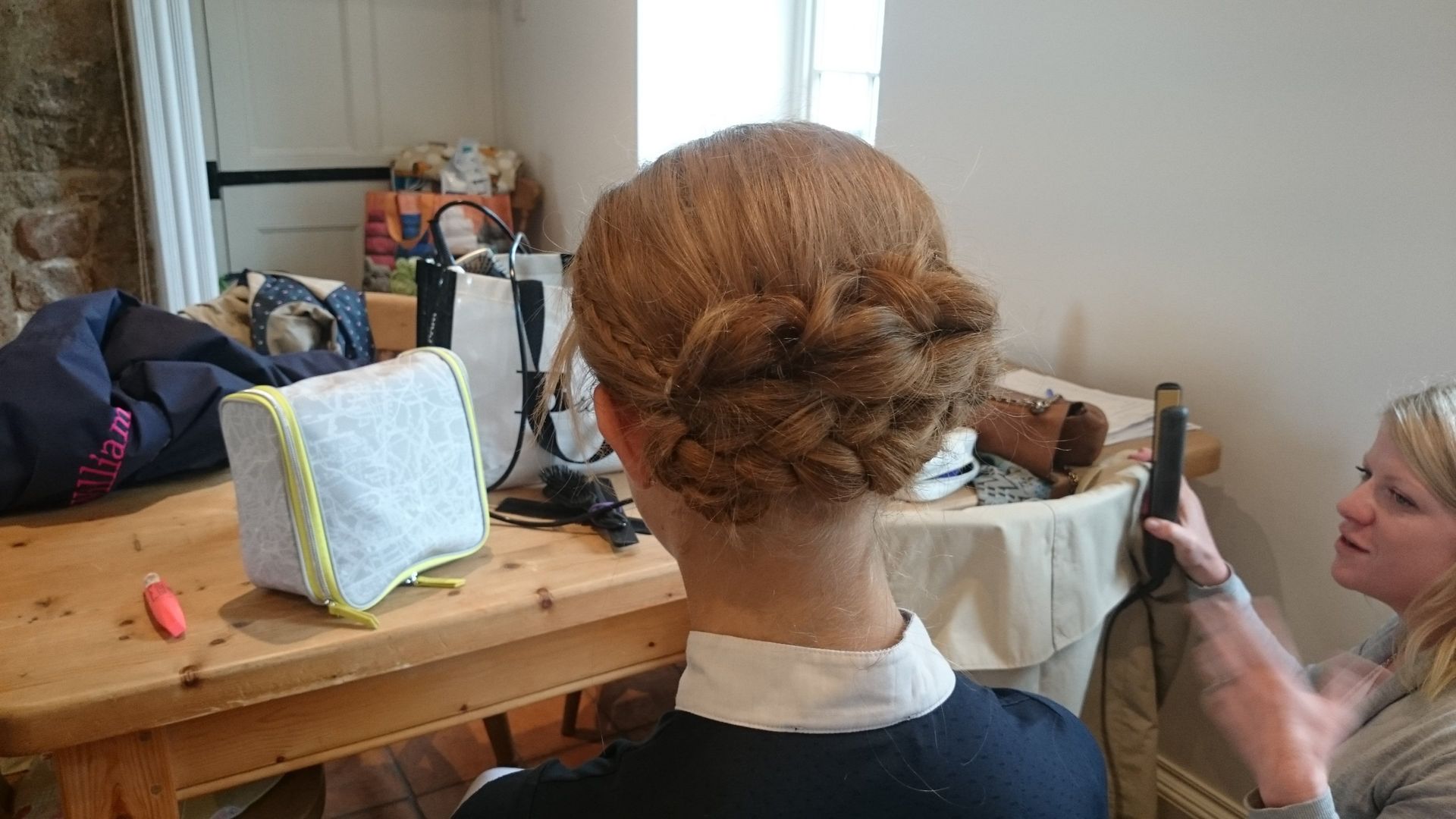 Woman with elaborate braided updo hairstyle, being styled indoors.