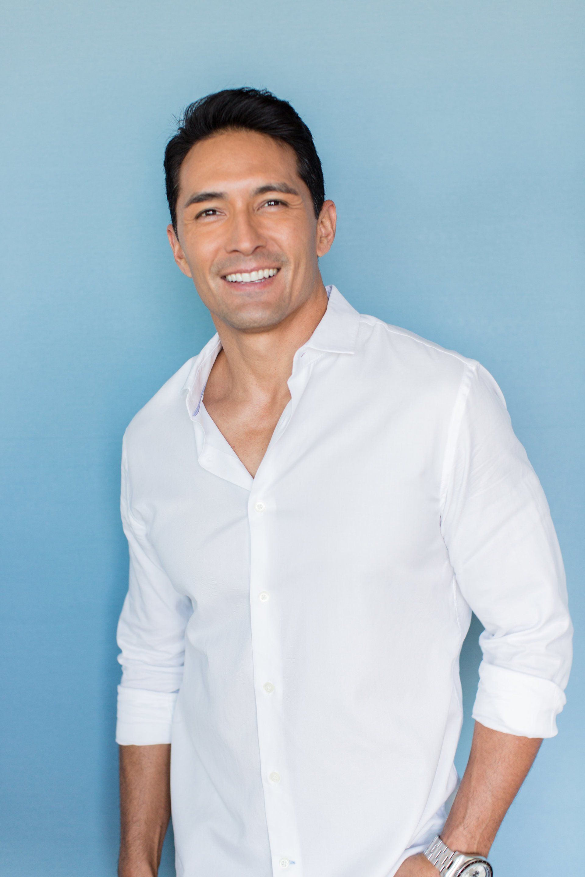 Smiling person in a white shirt against a light blue background
