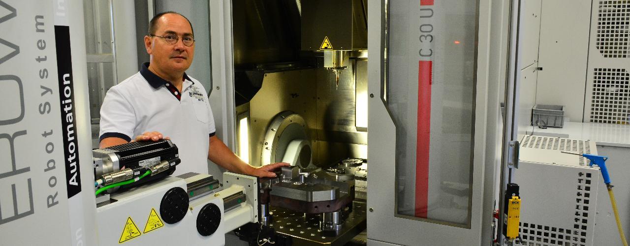 Een man staat voor een machine in een fabriek.