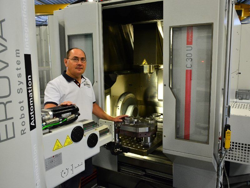 A man is standing in front of a machine that says robot system