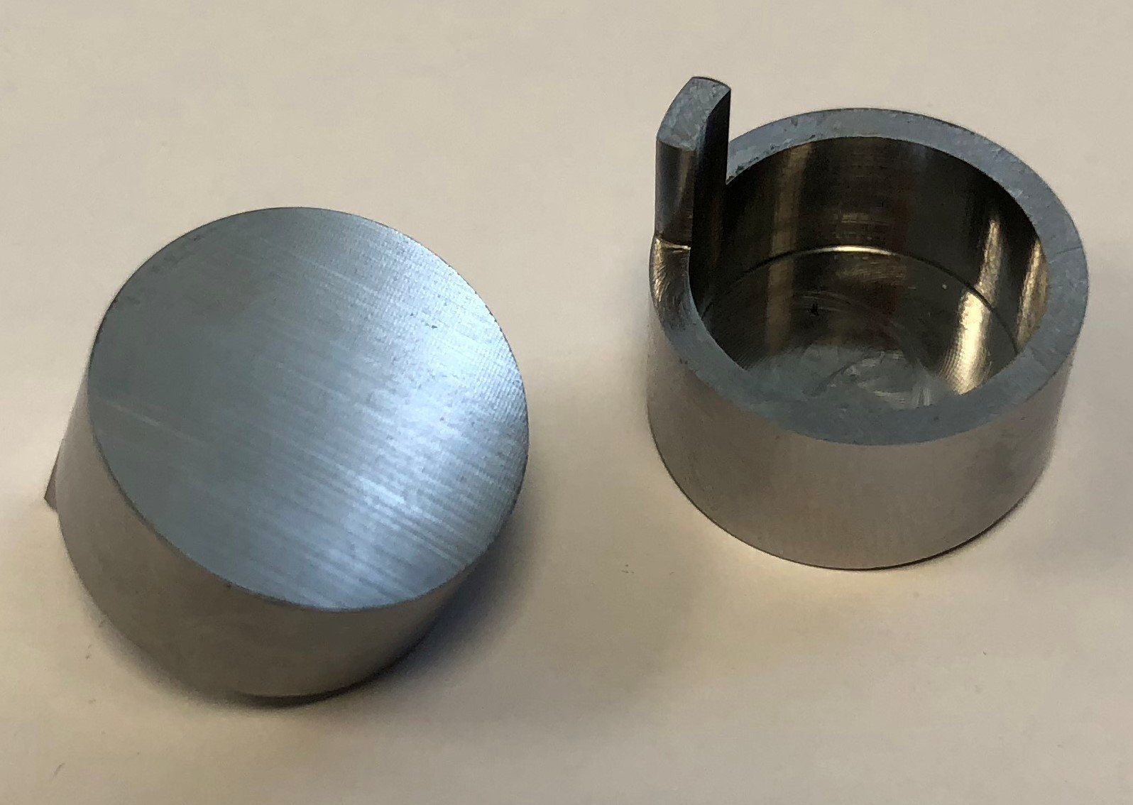Two metal cylinders are sitting next to each other on a white surface.