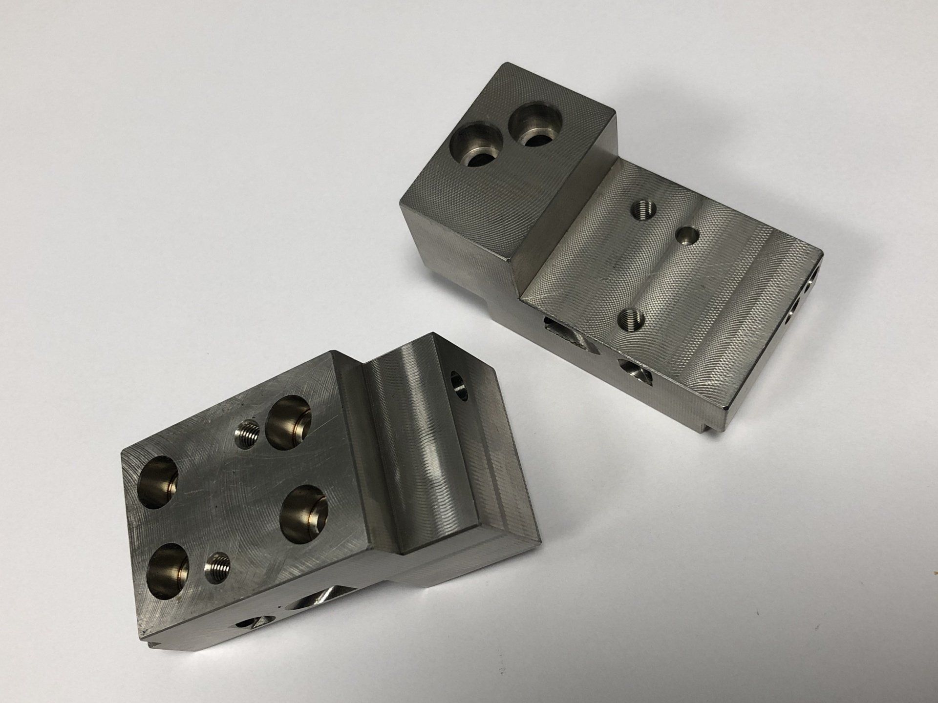 Two pieces of metal are sitting on a white surface.