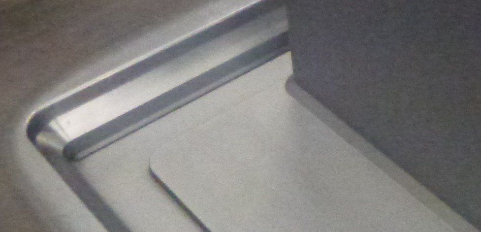 A close up of a stainless steel sink in a bathroom.