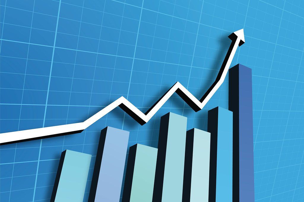 Bar graph with an upward-trending white line over it on a blue background, indicating growth.