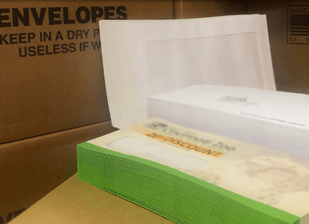 Open envelope box with white papers and a green stack of documents.