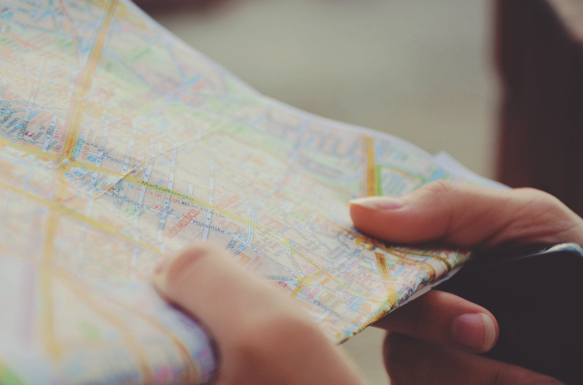 Hands holding a detailed paper map, possibly outdoors.