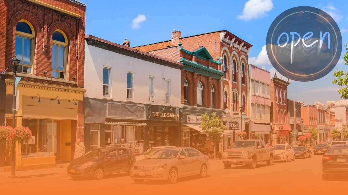 Downtown street with parked cars, brick buildings, and an