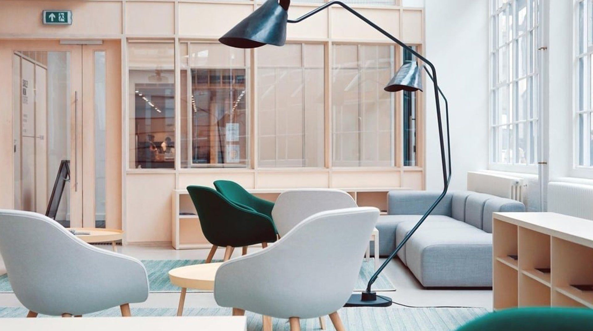 Bright modern lounge with pastel chairs, sofas, floor lamps, and large windows.