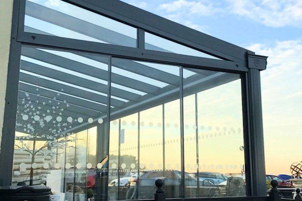 A dark-framed glass outdoor enclosure or patio cover with decorative white dots on the glass panels.