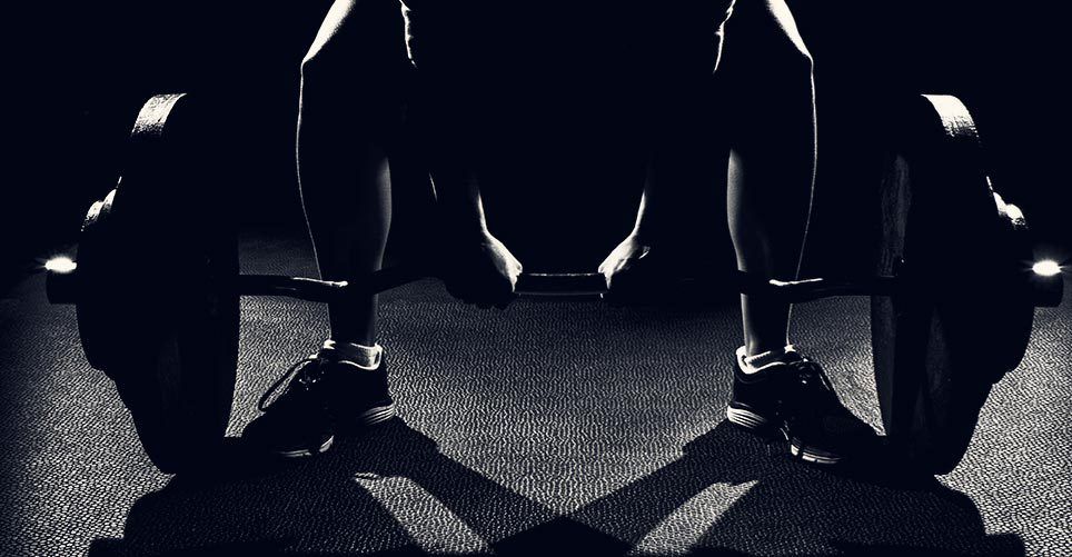A black and white photo of a person lifting a barbell.
