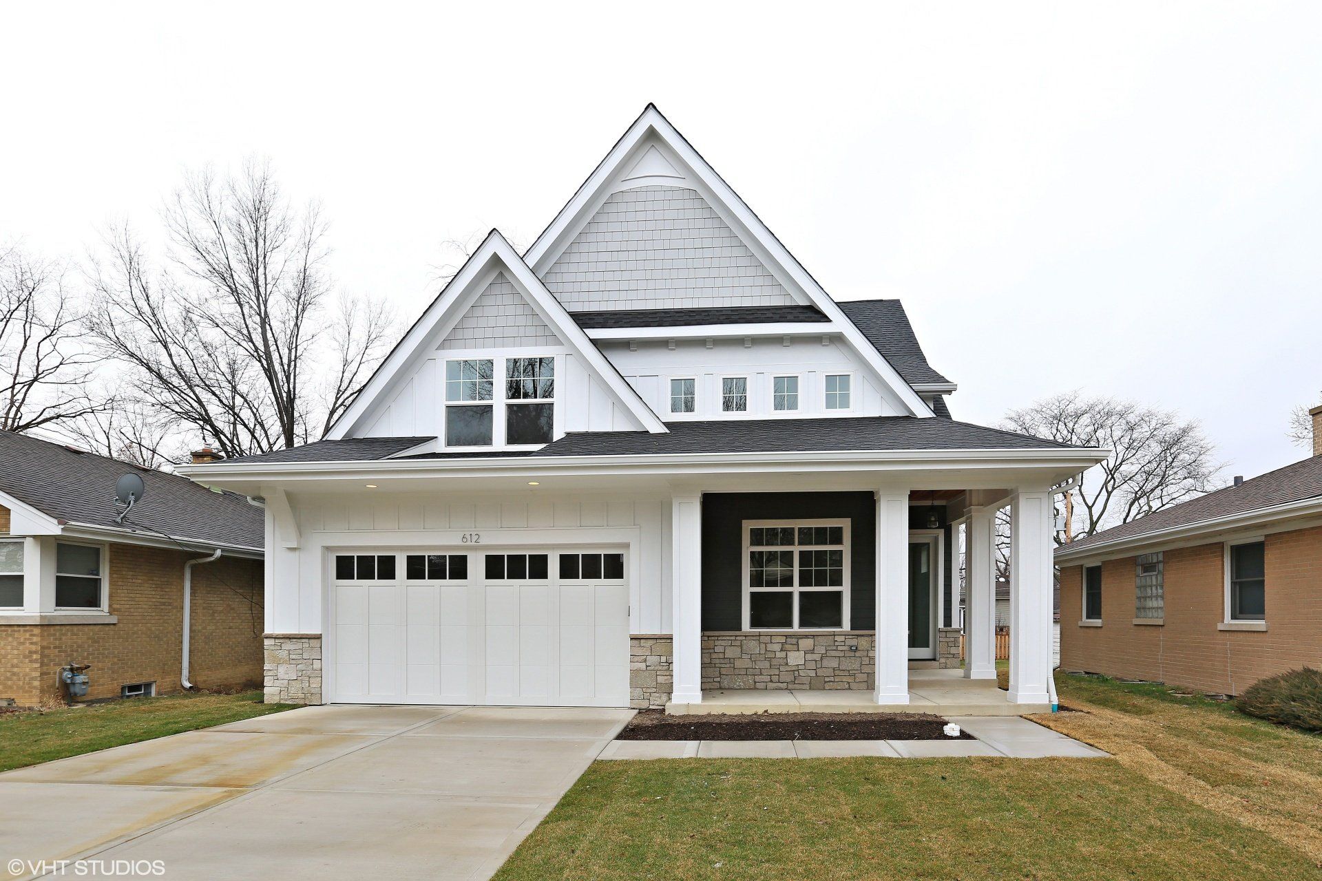A large white house with a black roof and a white garage door