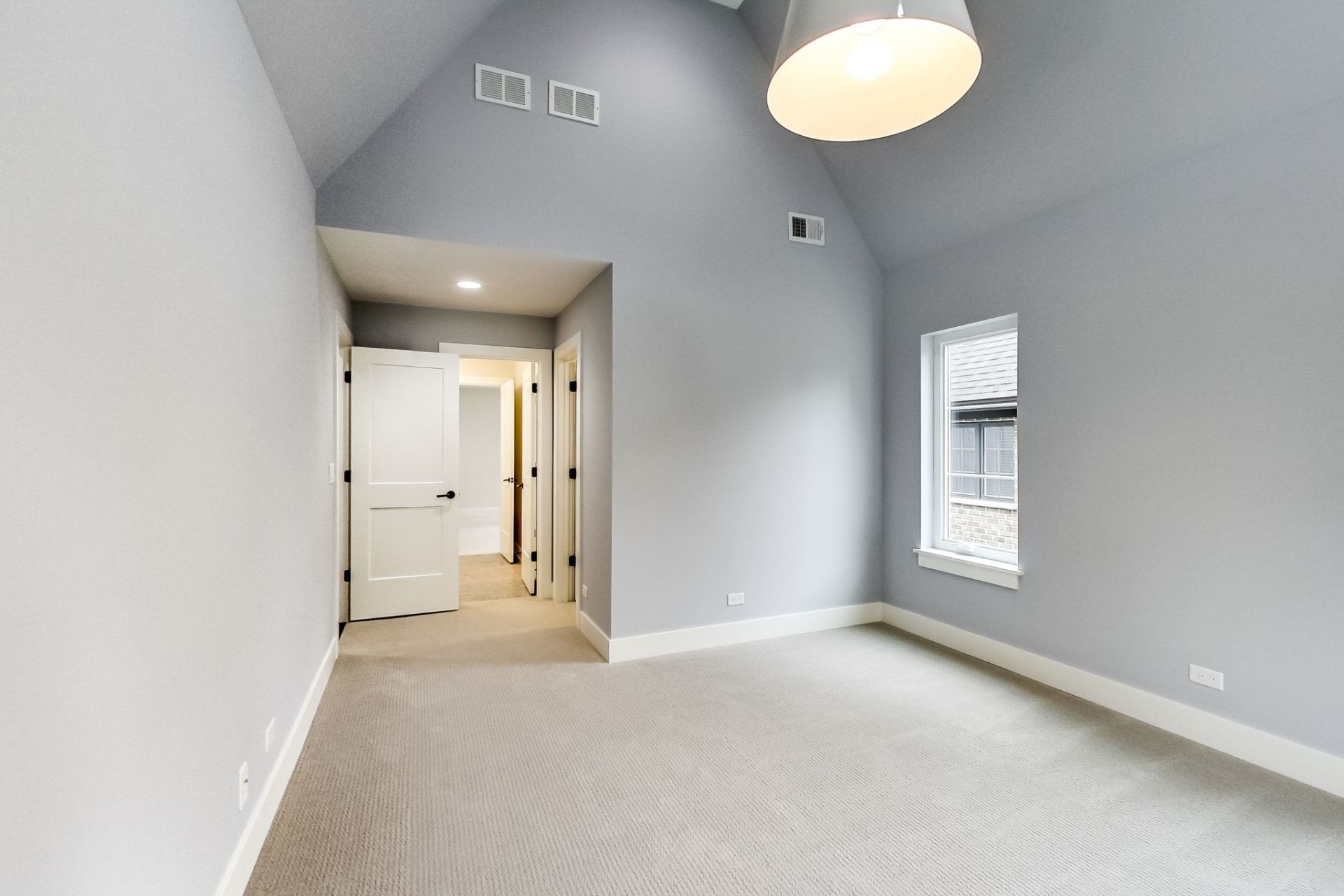 An empty room with a vaulted ceiling and a lamp hanging from the ceiling.