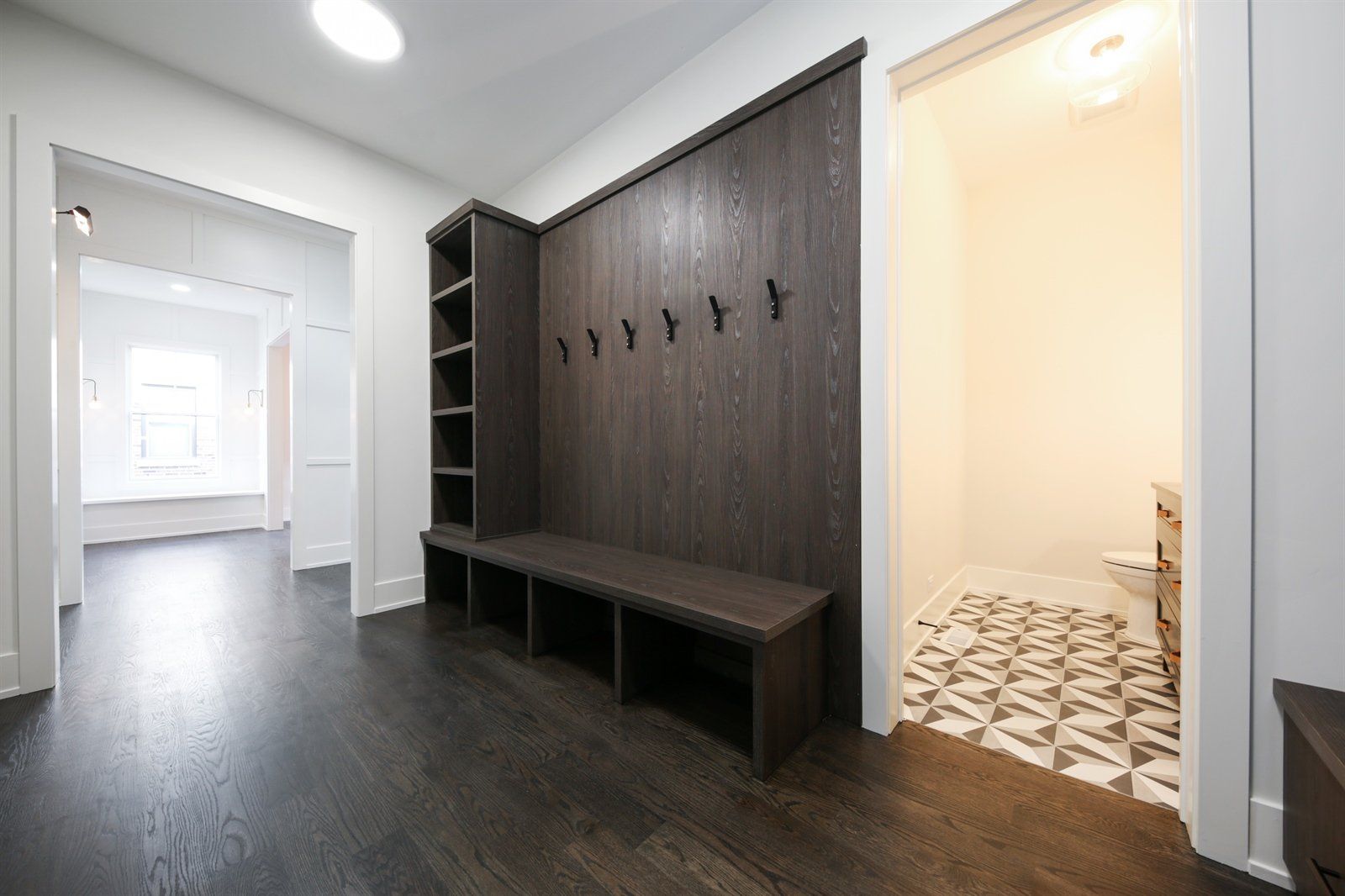 A hallway with a bench and hooks on the wall.
