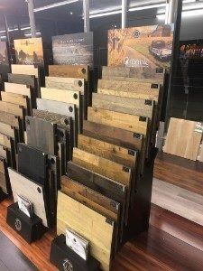 Display of various wood flooring samples in a store, arranged in rows with information cards.
