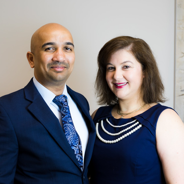 Two people posing indoors in formal attire, smiling at the camera.