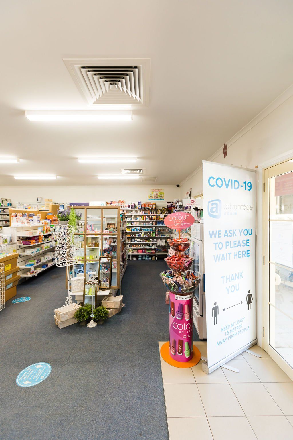 Interior of a small shop with shelves of goods and a COVID-19 safety sign near the entrance
