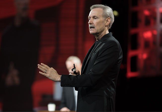 A man in a black suit is giving a speech