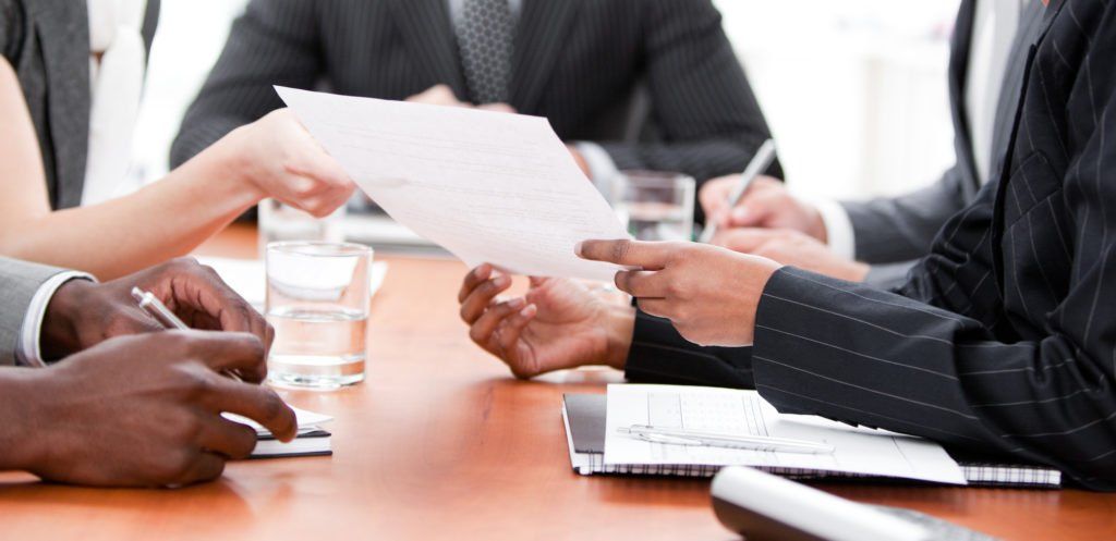 A group of people are sitting around a table looking at a piece of paper.