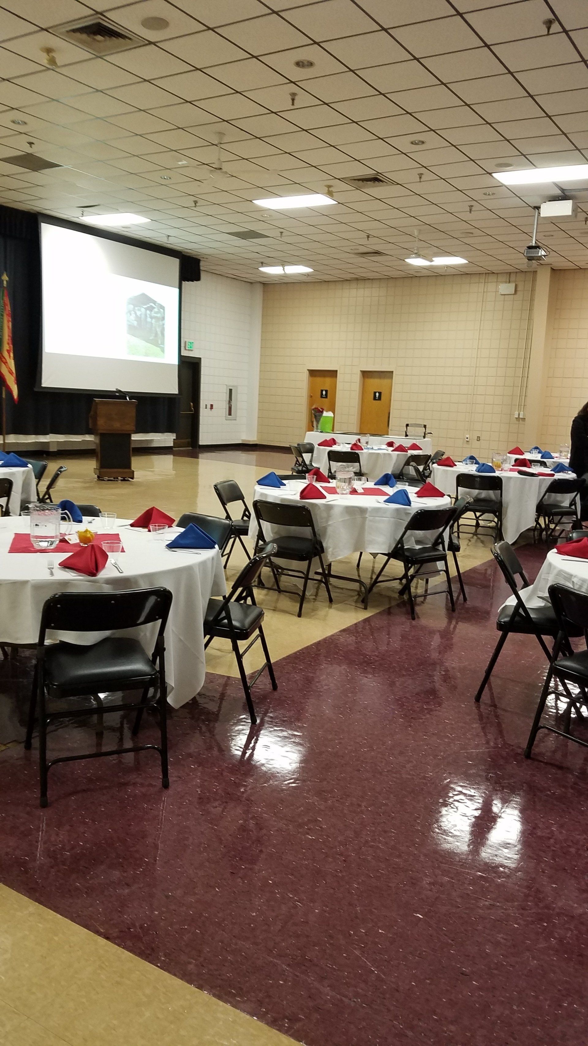 A large room with tables and chairs set up for a party.