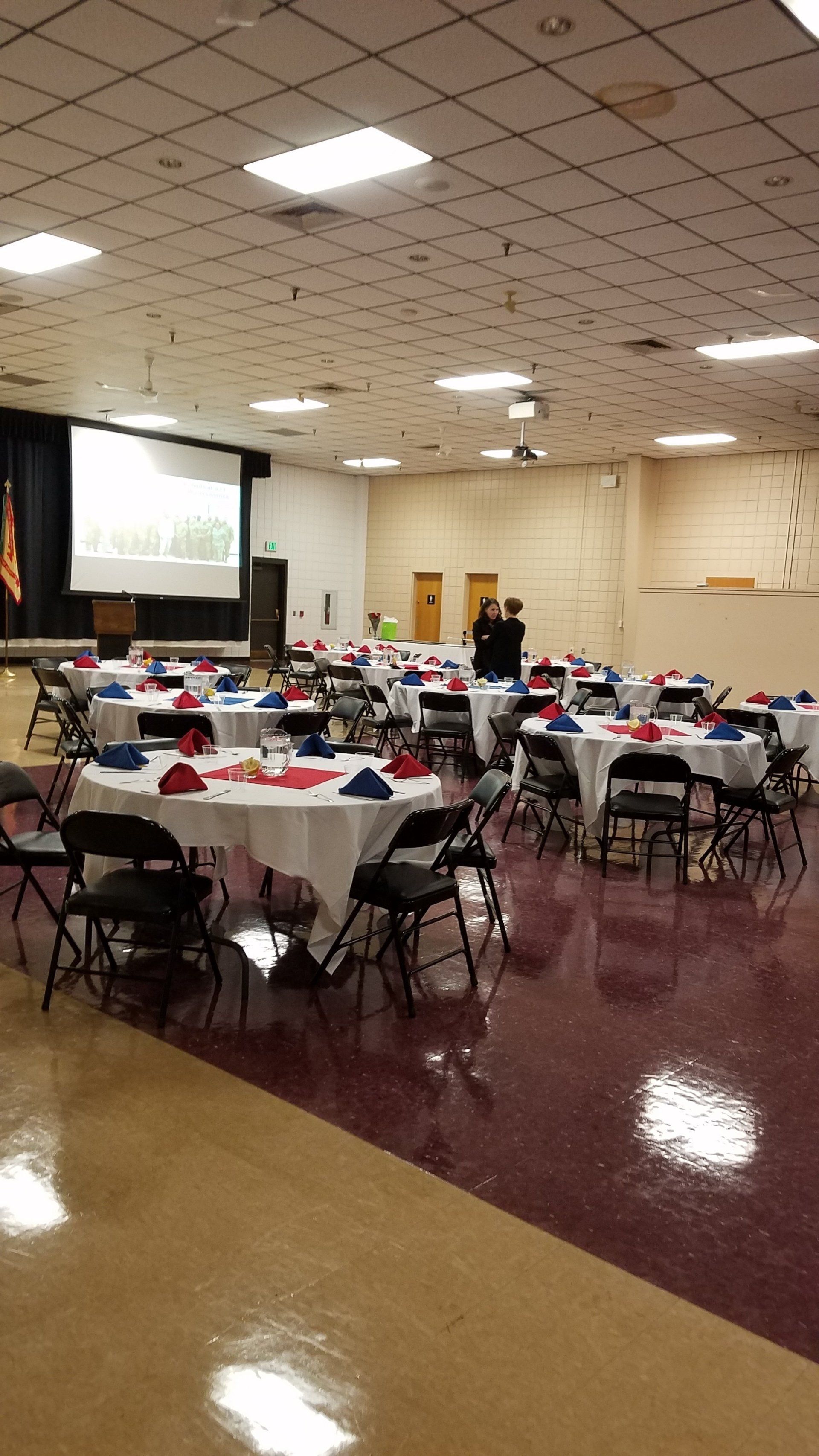 A large room with tables and chairs set up for a party.