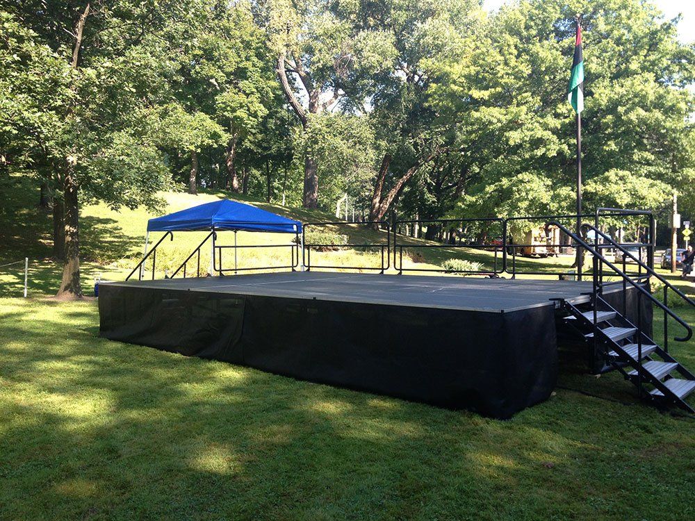 a stage with stairs and a blue tent in the background