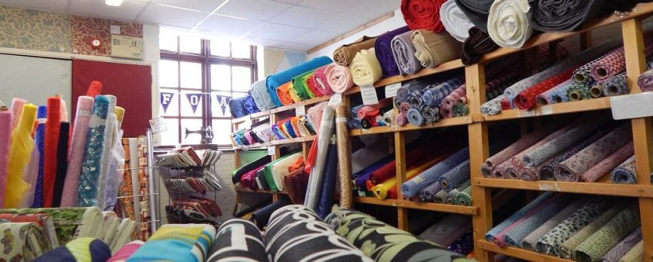 Shelves stacked with colorful fabric rolls inside a fabric store, showcasing a wide variety.
