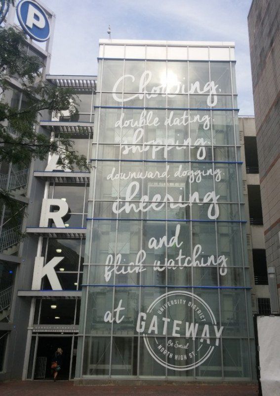 Glass storefront with handwritten white message and “GATEWAY” sign on a building facade
