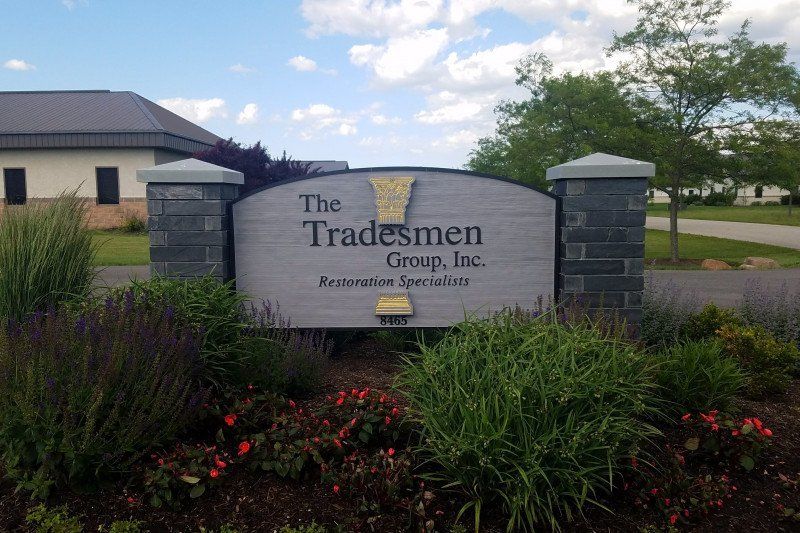 Stone sign for The Tradesmen Group, Inc. in a landscaped office park entrance