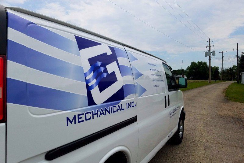 White mechanical service van with blue logo parked beside a dirt road under a cloudy sky
