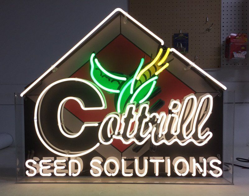 Neon Cottrill Seed Solutions sign with green and white lettering on a dark wall