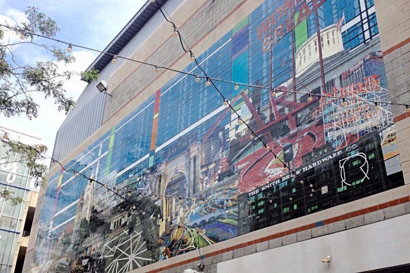 Large colorful mural on an exterior wall depicting a cityscape and industrial scene