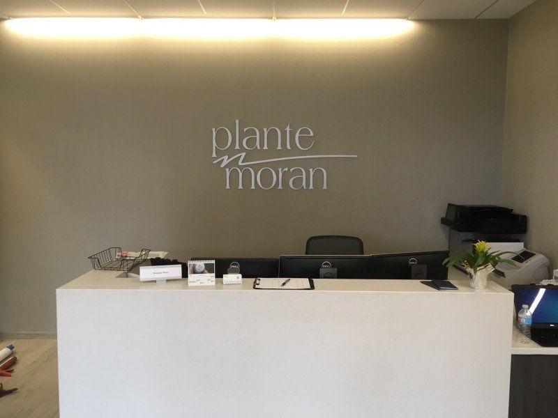 Modern office reception desk with “plante Moran” sign on a gray wall