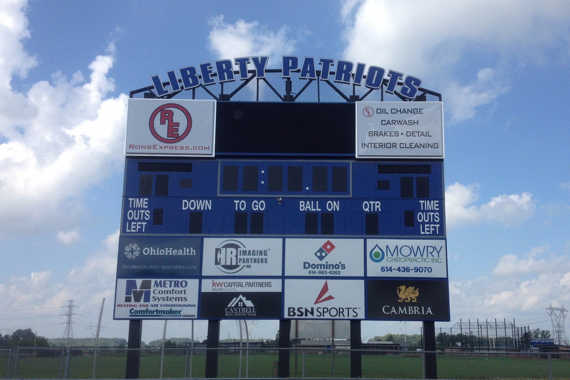 Liberty-Bank Park scoreboard under a cloudy sky on a grassy field