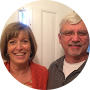 A smiling couple posing together in front of a white door.