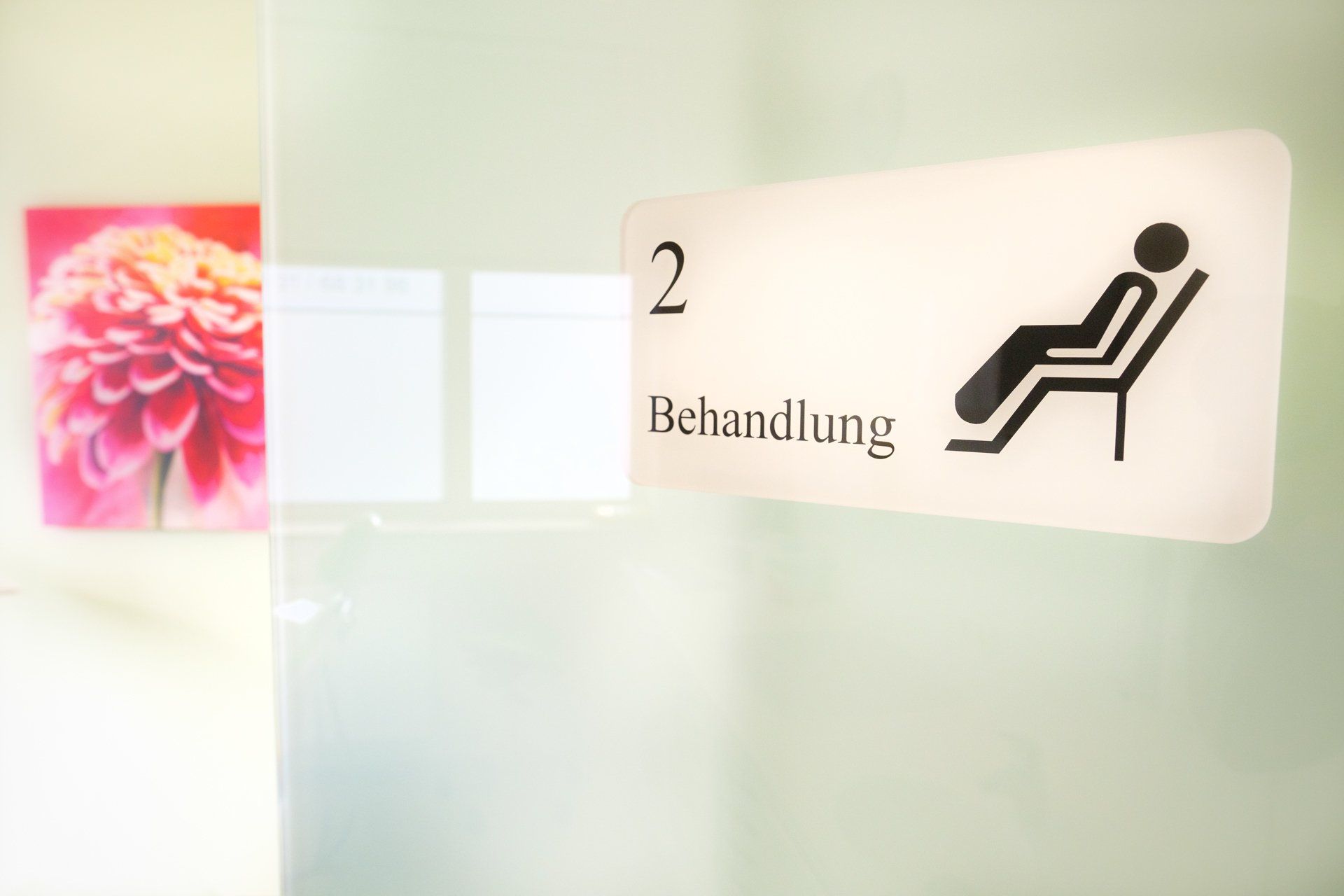 Eine Person sitzt auf einem Stuhl neben einem Schild mit der Aufschrift „Behandlung“.