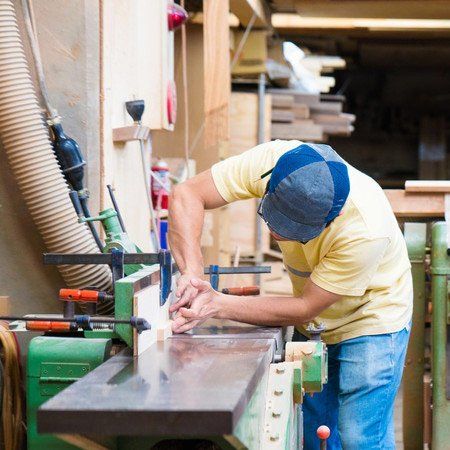 Craftsman using machine to cut wood in his workshop