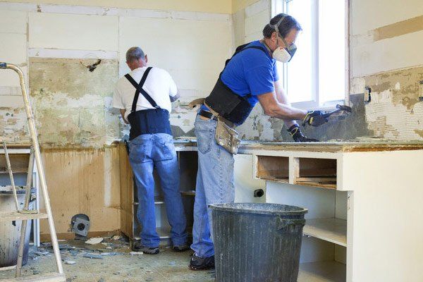 Two men tearing out old kitchen during home renovations.