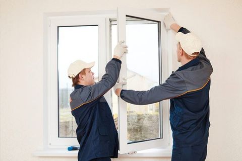 construction workers glaziers installing glass window indoor