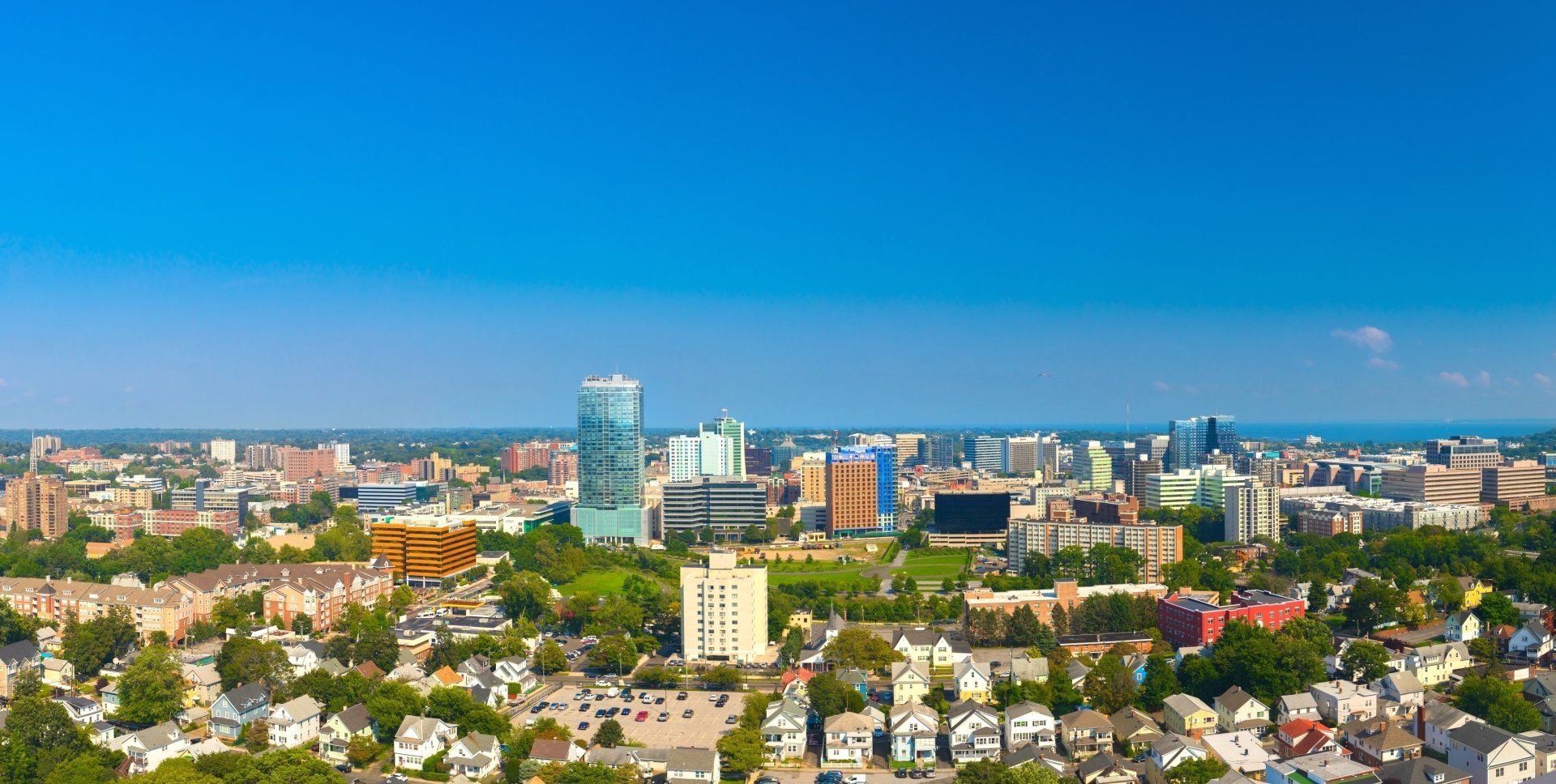 An aerial view of a city with lots of buildings and trees on a sunny day.