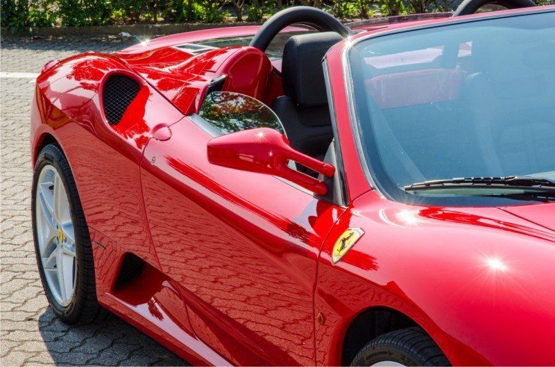 Ein roter Ferrari-Sportwagen ist im Freien geparkt; man sieht die Vorderseite und die Windschutzscheibe.