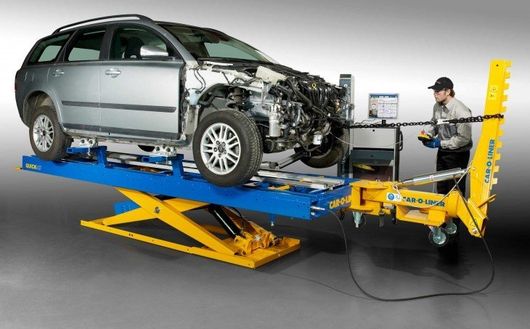 Silbernes Auto auf einem gelben Crashtest-Prüfstand, das einen Frontalkollisionstest im Labor zeigt.